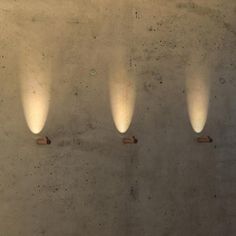 three light fixtures are on the wall in a room with concrete walls and cement flooring