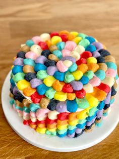 a multi colored cake sitting on top of a white plate covered in gummy bears