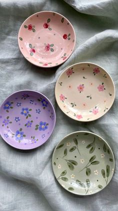 three bowls with flowers painted on them sitting on a bed