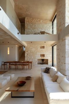 a living room filled with white couches next to a dining table and stairs leading up to an open floor plan