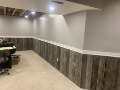 an empty room with wood paneling on the walls and a computer desk in the corner