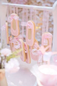 some cookies that are hanging from strings with pink bows on them and ribbons around them