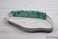 a green and white flowered headband sitting on top of a wooden table