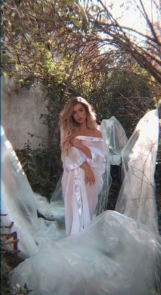 a woman in a white dress posing for the camera with plastic wrapped around her body