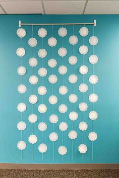 a blue wall with white paper flowers hanging from it