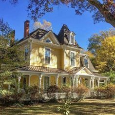 a large yellow house sitting on top of a lush green field