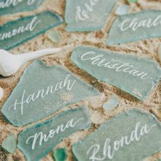 sea glass name tags on the sand with shells