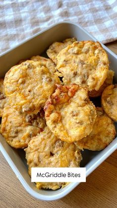 some biscuits are in a white dish on a wooden table with a checkered cloth