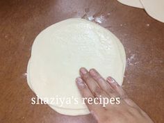 a person kneading dough on top of a wooden table