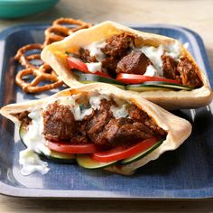 two meat pitas with yogurt sauce on a blue plate