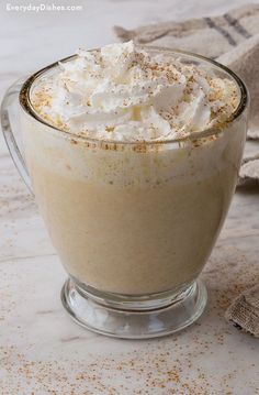 a glass cup filled with whipped cream on top of a table