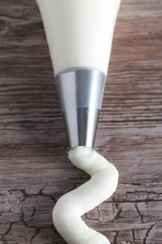 a close up of a white object on a wooden table with wood grain and metal handle