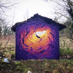 a brick building with a painted tiger face on it's side in the woods