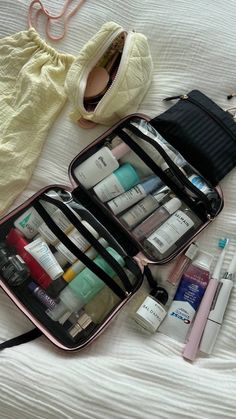 an open suitcase sitting on top of a bed filled with cosmetics and other personal care items