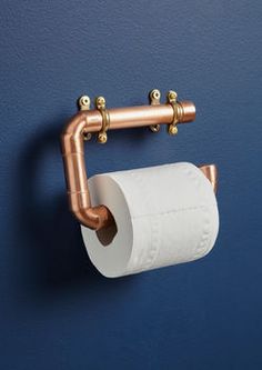 a roll of toilet paper is hanging on the wall next to a copper metal pipe