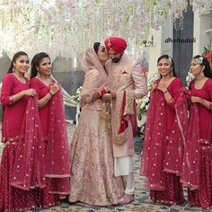 the bride and groom are kissing in front of their bridal party guests wearing red outfits