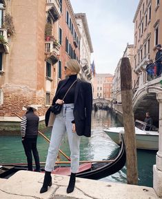 a woman standing on the edge of a boat in venice, italy while another person stands near her