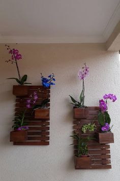 three wooden planters with purple and blue flowers in them hanging on the side of a wall