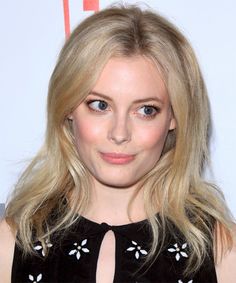 a woman with blonde hair and blue eyes wearing a black dress posing for the camera