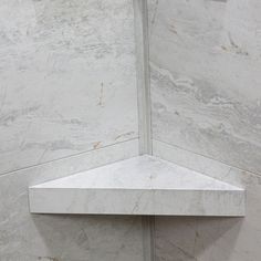 the corner of a white marble shower stall