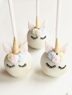 three cake pops with unicorn faces and flowers on them