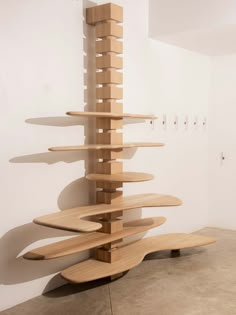 a sculpture made out of wooden planks in a room with white walls and concrete flooring