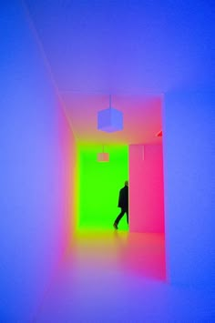 a person walking through a brightly lit room with neon colors on the walls and ceiling