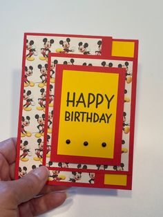 a hand holding up a birthday card with mickey mouse on it