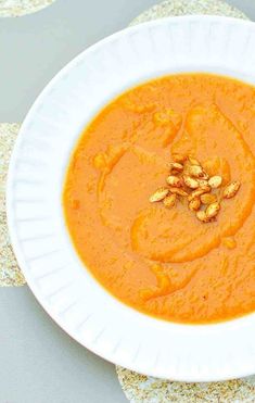 a white bowl filled with carrot soup on top of a table