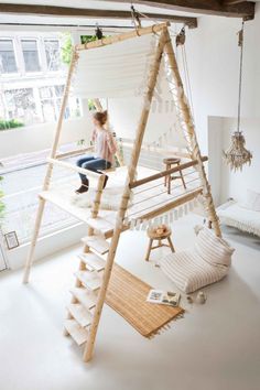 a child sitting on a swing bed in a room with white walls and flooring