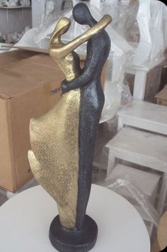 a gold and black figurine sitting on top of a white table next to a cardboard box