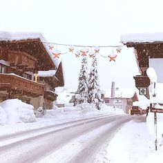 a snowy street lined with houses covered in snow and garlands hanging from the roof