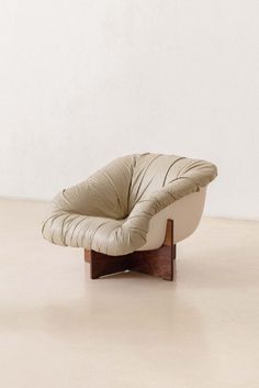 a white chair sitting on top of a floor next to a wooden frame and wall