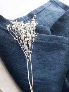 a t - shirt with dried flowers sitting on it's lapel, next to a pair of jeans