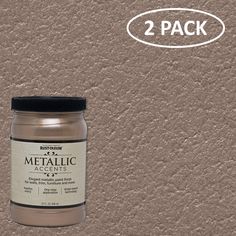 two jars of metallic paint sitting next to each other on top of a brown wall