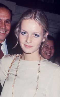 a man standing next to a woman in a white dress and smiling at the camera