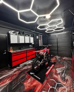 a motorcycle is parked in a garage with red and black paint on the floor,