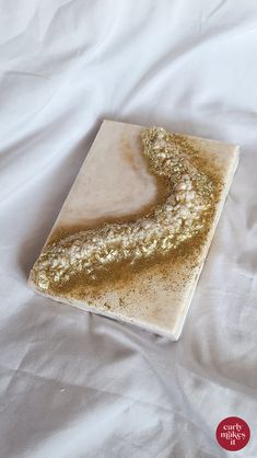 a white plate topped with gold glitter on top of a white bed cover covered in sheets