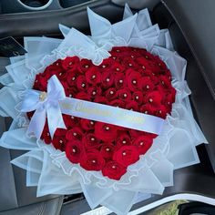 a heart - shaped box filled with red roses is sitting in the back seat of a car