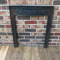 an old fireplace with wood flooring in front of a brick wall