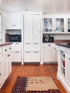 a kitchen with white cabinets and wooden floors