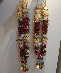 two red and white flowers are hanging on the wall next to each other with ribbons