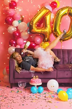 a woman laying on top of a purple couch next to balloons and confetti