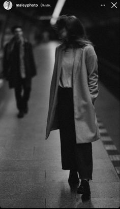 a woman walking down a sidewalk next to a train