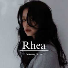 a woman with long black hair standing in front of a white wall and the words rheea flowing river