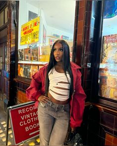 a woman standing in front of a store with her hands on her hips and looking at the camera