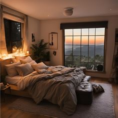 a bedroom with a large bed and window overlooking the mountains at sunset or dawn,