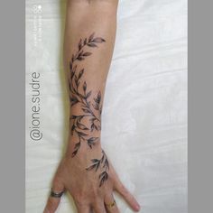 a woman's hand with a tattoo on it that has leaves growing out of it