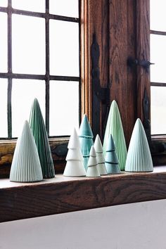 five small ceramic trees sitting on top of a window sill