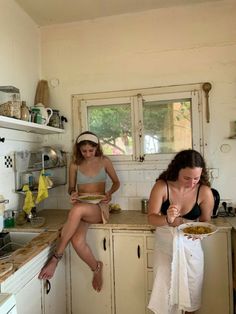 two women sitting at a kitchen counter eating food